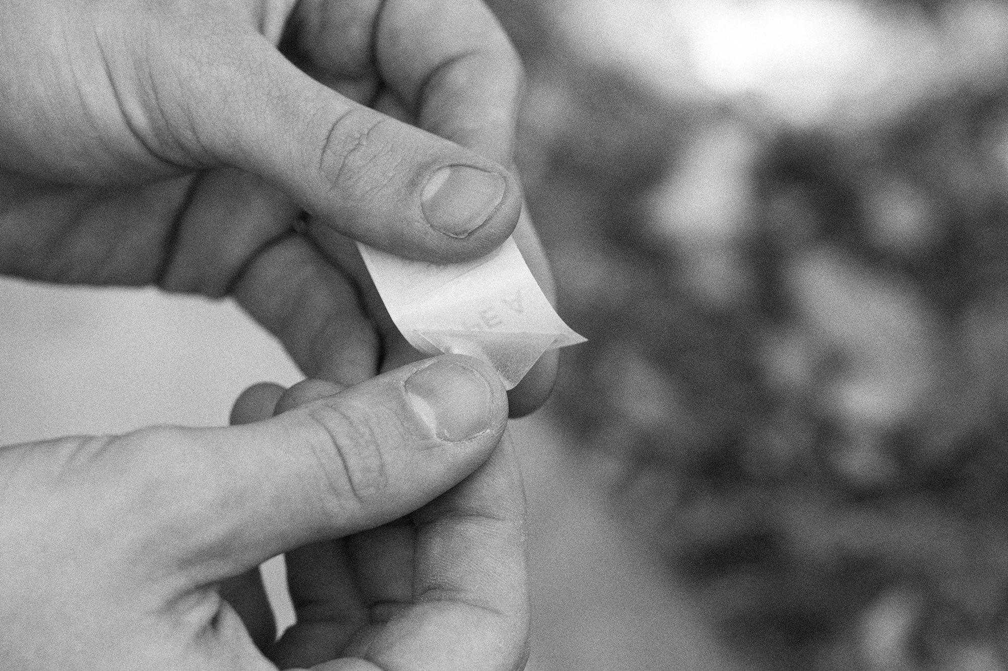 Peeling a clear TPU repair patch from its paper backing before patching a sleeping pad