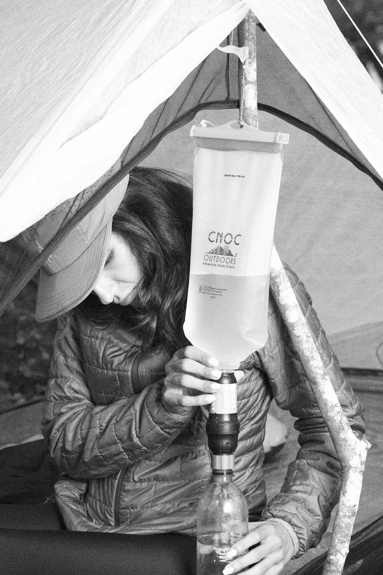 Platypus QuickDraw and Sawyer Squeeze water filters laid out on a tent floor beside a filled reservoir